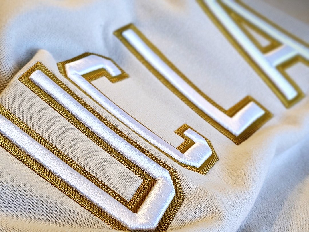 Close detail of white UCLA lettering with gold embroidery on fleece